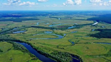 Drone, öğleden sonra vakti nehri olan güzel bir yaz manzarasının üzerinde uçar. Gökyüzünde kümülüs olan uçaklar inanılmaz bir arazinin üzerinde uçuyor. Nehre kuş bakışı. Havadan sinematik görünüm.