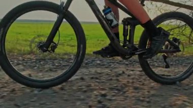Erkek ayağının yavaş hareketi bir dağ bisikletinin pedallarını çevirir. Çakıl taşları üzerinde bisiklet tekerleğinin yakın çekimi. Bisiklet tekerleği hareket halindeyken çekilen çekim. Bisikletçi bisikletle pedal çeviriyor. Bisiklet lastiği 