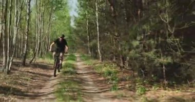 Orman yolunda bisiklet sürerler. Ormanda bisiklete binen bir adam. Bisiklet kasklı yetişkin bir adam yazın MTB bisikletine biner..