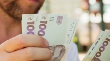 Sinematik çekim: Erkekler Ukrayna 'nın parasının 1000 hryvnia değerinde olduğunu düşünürler. Kişi banknotları sayar. Adam bir tomar para sayıyor. Paralı insan elleri.