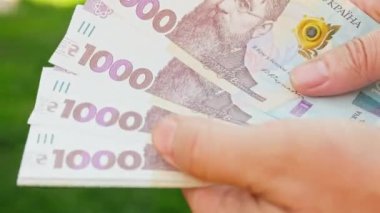 Sinematik çekim: Erkekler Ukrayna 'nın parasının 1000 hryvnia değerinde olduğunu düşünürler. Kişi banknotları sayar. Adam bir tomar para sayıyor. Paralı insan elleri.