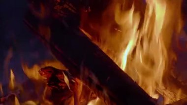 Ormanda büyük bir yangın var, gece vakti. Ağır çekim, gece kamp ateşine yakın çekim. Büyük alevlerle alçak görüş açısı. Büyük bir sonbahar akşamında büyük odunların yanması. 