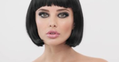 Moda modeli döner ve kameraya bakar. Smokey eyes makyajlı genç bir kadın. Seksi beyaz bir kızın yakın plan yüzü. Kısa saçlı, güzel bir esmer. Uzun kirpikleri olan etkileyici bir kız.. 