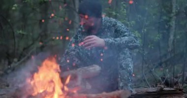 Ormandaki ateşin yanında sıcak çay içen bir adam. İnsan yaz aylarında orman yangınına bakar ve doğada çay içer. Yalnız gezgin ateşin yanında oturur ve alacakaranlıkta bir fincan kahveyle dinlenir.. 