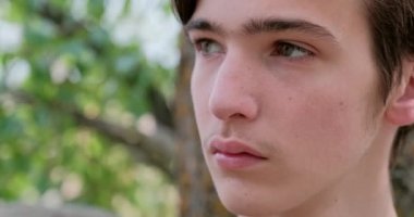 Genç üzgün adam başka yere bakıyor. Mutsuz, yalnız, genç bir delikanlı, açık havada. Hüzünlü bakışları olan yakışıklı bir adamın yakın çekim yüzü. Hüsrana uğramış genç yüzü, dışarıda.. 