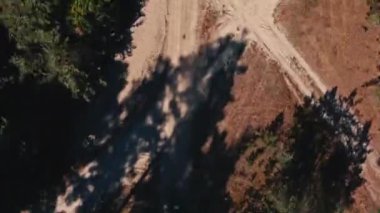 İHA 'dan gelen hava görüntüsü, bir ralli aracını takip ediyor. Fast Buggy büyük toz bulutlarıyla gidiyor. İnsansız hava aracından orman yolundaki ırka üstten görüntü.