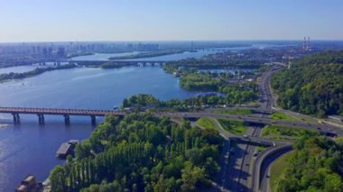 Kiev 'de yaz sabahında yol kavşağının üstündeki hava manzarası. İnsansız hava aracı sürüş arabalarıyla otoyolun üzerinden uçuyor. Kiev 'in Dnepr nehri boyunca uzanan köprülerinin üst görüntüsü. 