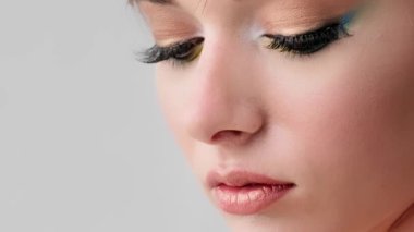 Sinema yavaş çekim görüntüsü. Genç bir kadın gözlerini açar ve kameraya bakar. Parlak, modaya uygun, şık bir makyaj. Uzun kirpikli ve canlı makyajlı yakın kadın gözleri.