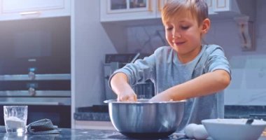 Yavaş çekim 4K, çocuk mutfakta yemek pişiriyor. Beyaz çocuk kurabiye için elleriyle hamur karıştırıyor. Çocuk, çelik kasede kek malzemelerini karıştırıyor. 8 yaşındaki çocuk evde yemek pişiriyor.. 