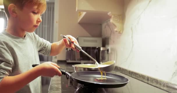 小男孩在厨房里做饭 孩子们从勺子里把煎饼的混合物倒入锅里 慢动作童年概念 — 图库视频影像