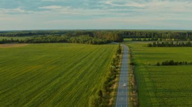 Hava aracı gün batımında arazi aracı ile otobanın üzerinde uçuyor. Otomobilli bir banliyö yolunun havadan görünüşü. Arabalı bir yol manzarası. Otobanda bir aracın hava görüntüsü. 