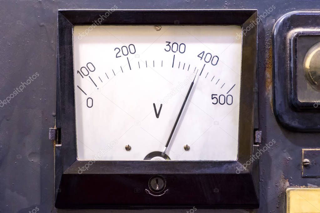 The device is an analog voltmeter vintage in the instrument panel, close-up.