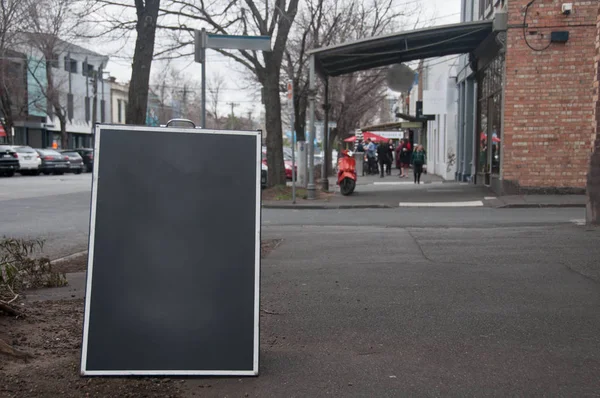 一家房地产公司放置在街道上的黑色木制招牌 — 图库照片