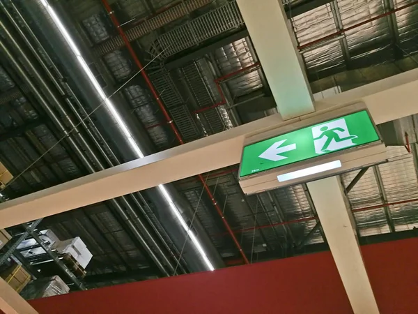 Señal de ruta de salida de emergencia en la parte superior del almacén de fábrica Imagen de stock