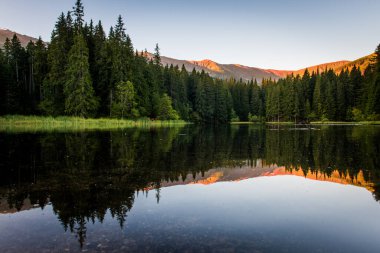 Dağları aydınlatan güzel bir manzara, dağ gölü yansıması, mavi gökyüzü ve sarı güneş ışığı. Slovakya, Vrbicke Pleso