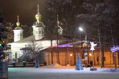 Sessiz, soğuk bir bayram akşamında katedral binasının arka planında şenlikli bir Noel ağacı var.