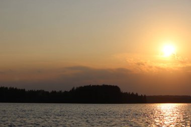 Gün batımında büyük bir gölün kıyısında renkli bir sonbahar ormanı.