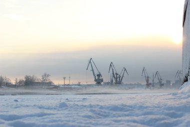 Akşamüstü bulutlu bir gökyüzü, bir sanayi limanı ve haliçinin arka planında.