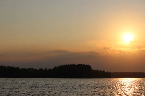 Gün batımında büyük bir gölün kıyısında renkli bir sonbahar ormanı.