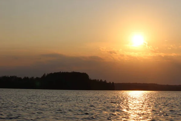 Sonbahar akşamında günbatımı büyük bir orman gölünün arka planında.