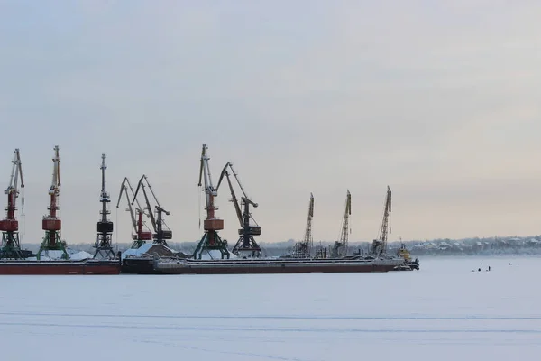 Soğuk bir kış gününde gün batımında bir kargo limanı ve donmuş bir nehre karşı