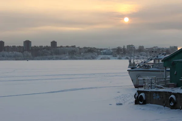 Soğuk bir akşamda, bulutlu gökyüzünde günbatımı endüstriyel liman ve nehir setinin arka planında.