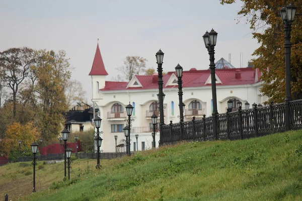 Sonbahar günü yeşil çayır üzerinde kırmızı çatılı beyaz renkli tek katlı bina.