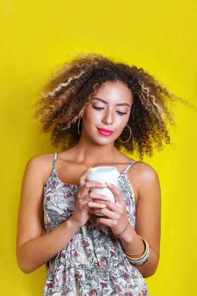 Retrato de belleza de una joven afroamericana con peinado afro. Chica posando sobre fondo amarillo, mirando a la cámara . — Foto de Stock