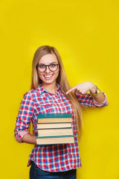 안경 및 캐주얼 밝은 옷에 노란색 배경에 책으로 서 젊은 세련 된 학생을 웃 고 — 스톡 사진