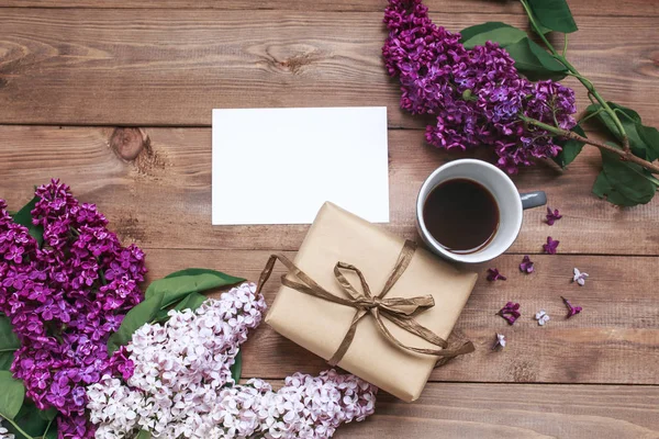 Ramo de flores lila sobre tablones de madera con tarjeta en blanco para texto y café —  Fotos de Stock