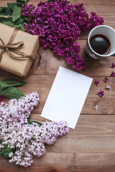 Ramo de flores lila sobre tablones de madera con tarjeta en blanco para texto, regalo y café. Vista superior —  Fotos de Stock