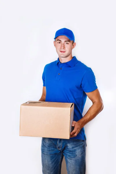 Um homem de entregas alegre. Feliz jovem mensageiro segurando uma caixa de papelão e sorrindo — Fotografia de Stock