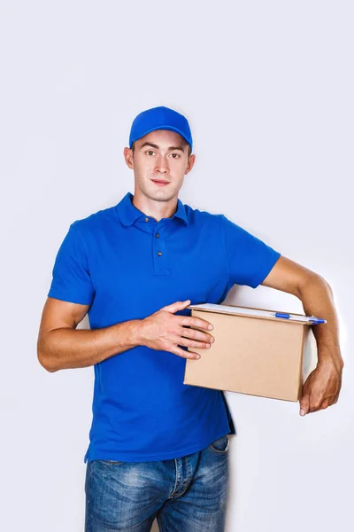 Vrolijke levering man. Gelukkig jonge courier holding een kartonnen doos en glimlachen — Stockfoto