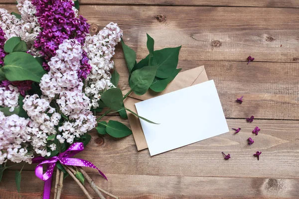 Ramo de flores lila sobre tablones de madera con tarjeta en blanco para texto. Vista superior —  Fotos de Stock