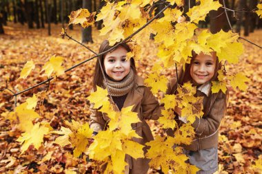 İki küçük kız oynar Park Sonbahar yaprakları