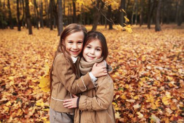 Sevimli iki küçük kız sonbahar parkta sarılma