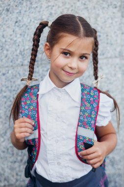 Elinde kitapla ilkokul öğrencisi. Açık hava binasının yakınında sırt çantalı bir kız. Dersler başlıyor. Sonbaharın ilk günü.