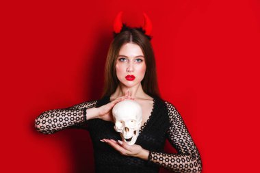 İçinde şeytan halloween kılık kafatası tutan orta esmer saçlı şehvetli beyaz genç kadın