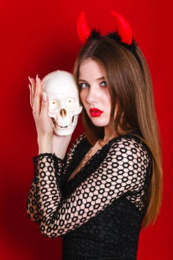 İçinde şeytan halloween kılık kafatası tutan orta esmer saçlı şehvetli beyaz genç kadın