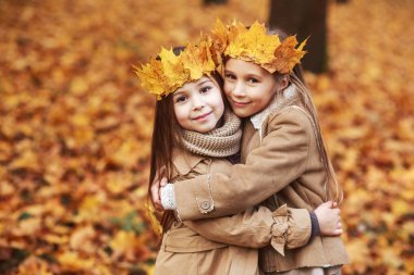 Kron sonbahar parkta sarılma yaprakların iki sevimli küçük kız