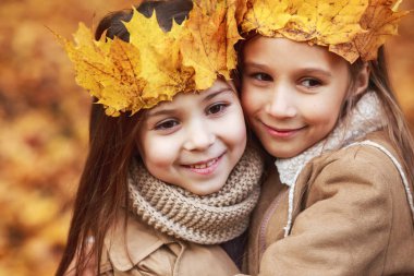 Kron sonbahar parkta sarılma yaprakların iki sevimli küçük kız