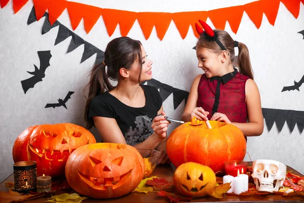 Fröhliches Halloween. Mutter und Tochter schnitzen Kürbis. Familie bereitet sich auf Urlaub vor. — Stockfoto