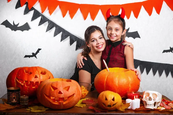 Grappige moeder en dochter plezier thuis. Voorbereiden van Halloween en gelukkige familie. Mensen die dragen carnaval kostuums. — Stockfoto
