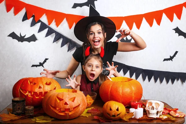 Vicces anya és lánya otthon érzik magukat. Boldog család felkészülés Halloween. Emberek visel Farsangi jelmezek. — Stock Fotó