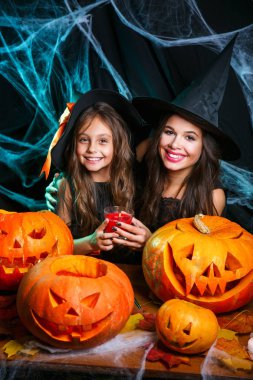 Cadılar Bayramı kavramı - Closeup güzel beyaz anne ve kızı cadı kostümleri Cadılar Bayramı ile eğri kabaklar örümcek web üzerinden poz kutluyor