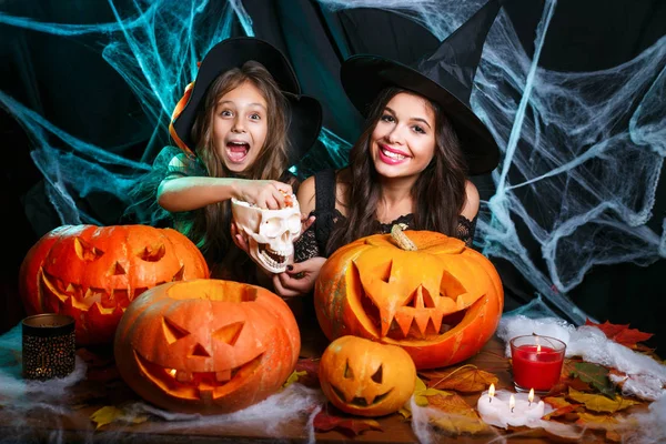 Vrolijke Halloween. Mooie Kaukasische moeder met gelukkig weinig dochter genieten met Halloween snoep en zoet over vleermuizen en spinnenweb op zwarte studio achtergrond. — Stockfoto