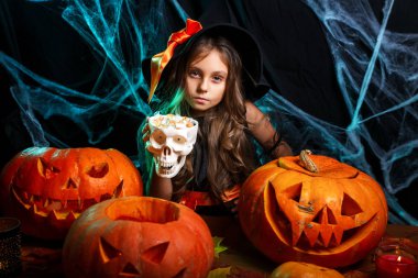 Halloween cadı kavramı - küçük cadı çocuk Cadılar Bayramı tatlı ve şeker neşeli örümcek ağı üzerinde gülümseyen ve eğri kabaklar arka plan ile.