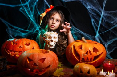 Halloween cadı kavramı - küçük cadı çocuk Cadılar Bayramı tatlı ve şeker neşeli örümcek ağı üzerinde gülümseyen ve eğri kabaklar arka plan ile.