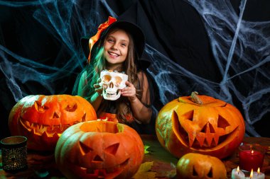 Halloween cadı kavramı - küçük cadı çocuk Cadılar Bayramı tatlı ve şeker neşeli örümcek ağı üzerinde gülümseyen ve eğri kabaklar arka plan ile.