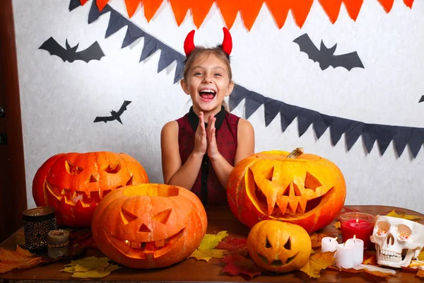 Happy halloween. Cute funny little child girl with carving pumpkin. Happy family preparing for Halloween.
